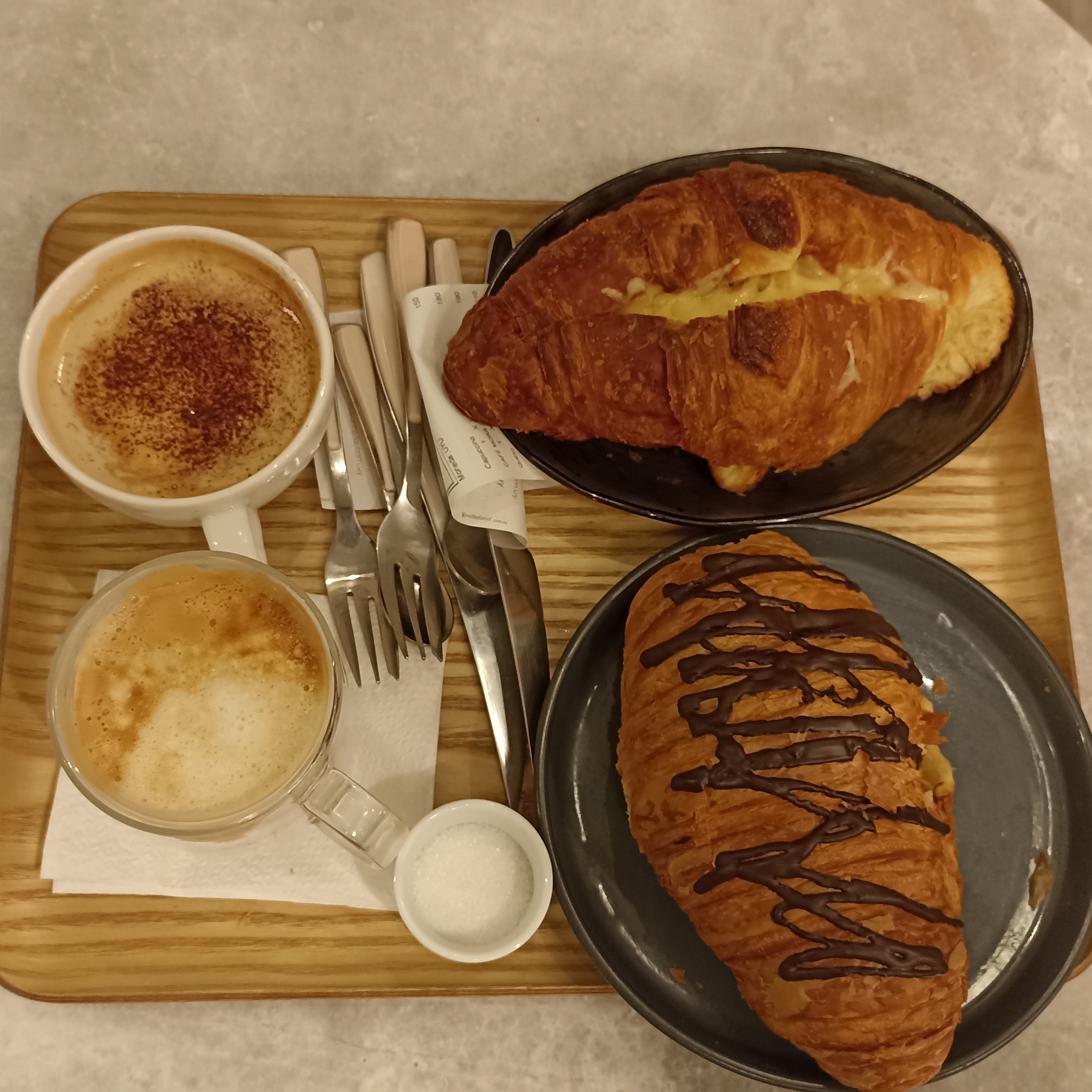 Imagen donde se muestran dos croissants junto a dos tazas de café, cafetería La Croissantería